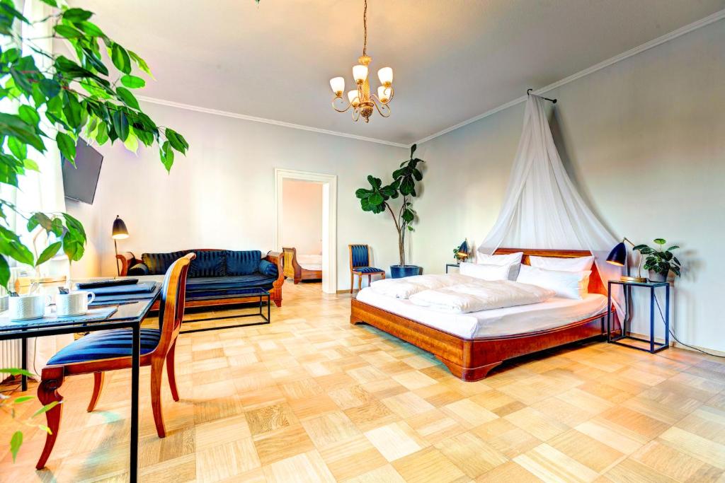 een slaapkamer met een bed, een tafel en een bank bij Hotel Villa Königsgarten in Siebeldingen