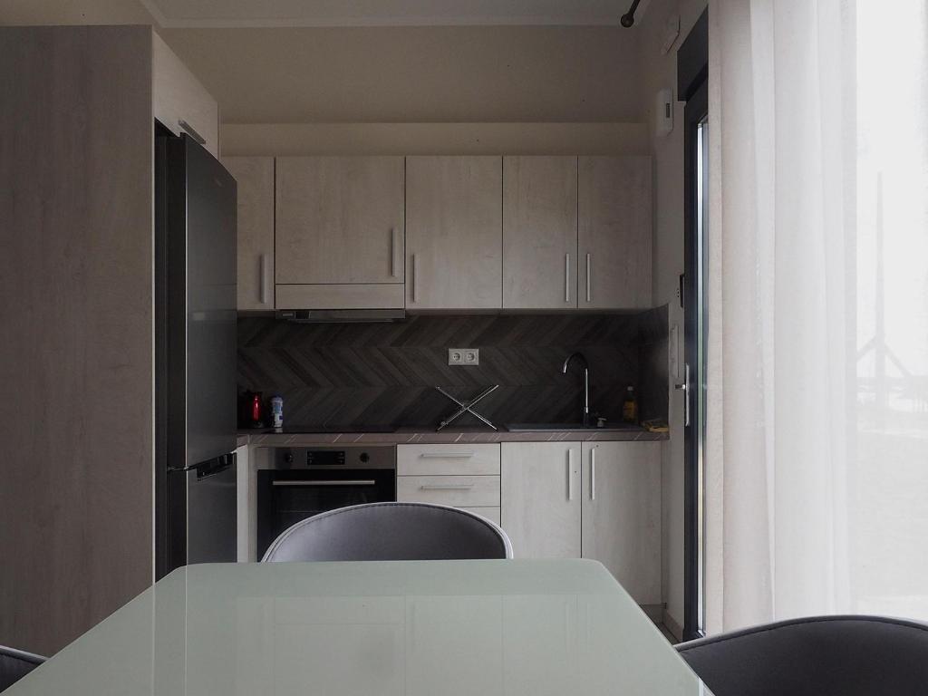 cocina con armarios blancos, mesa y sillas en Melissinos Beachfront Apartments, en Kómi