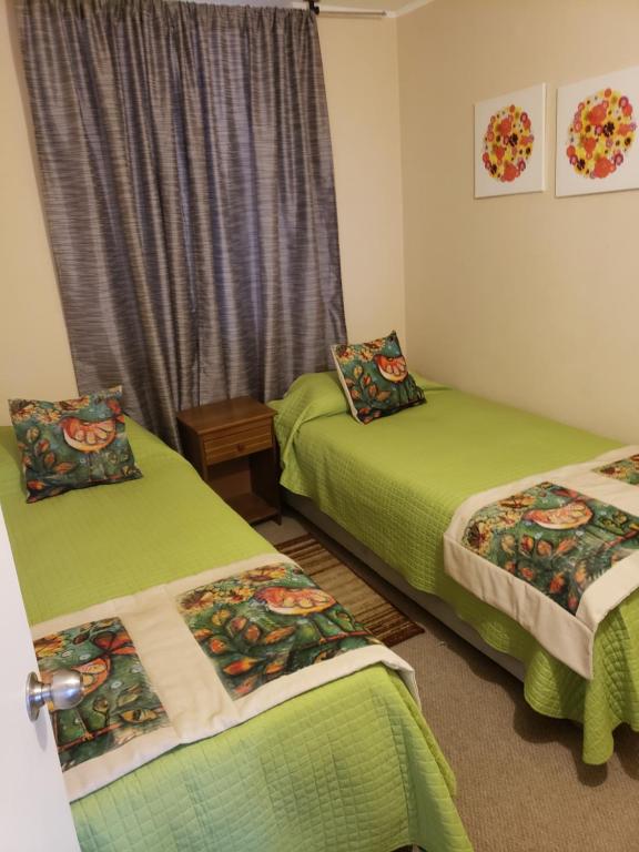 2 camas en una habitación con sábanas verdes en Departamento Tome, en Tomé