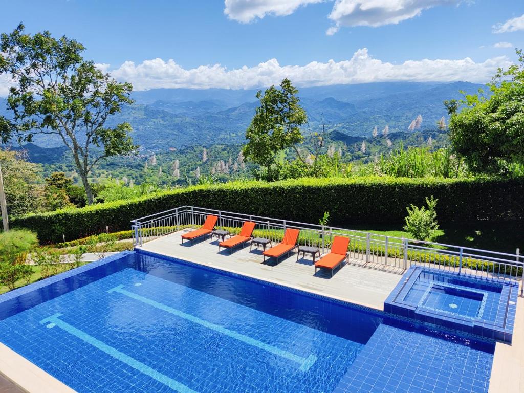 una piscina con sillas y vistas a las montañas en CasaMIA Hotel Boutique - Villeta, en Villeta