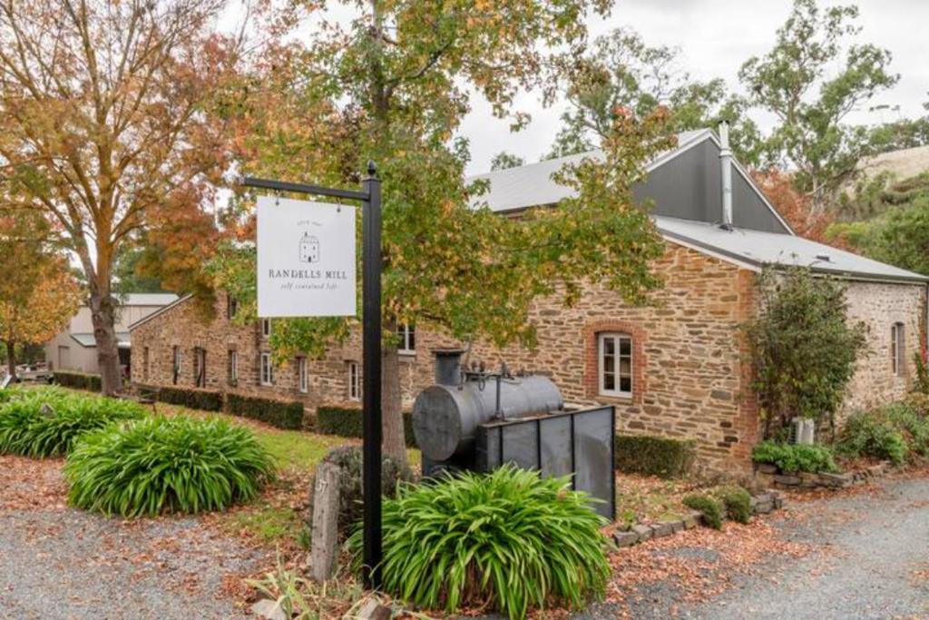 un bâtiment en briques avec un panneau devant lui dans l'établissement Randell's Mill - Adelaide Hills - Romantic Loft Stays, à Gumeracha