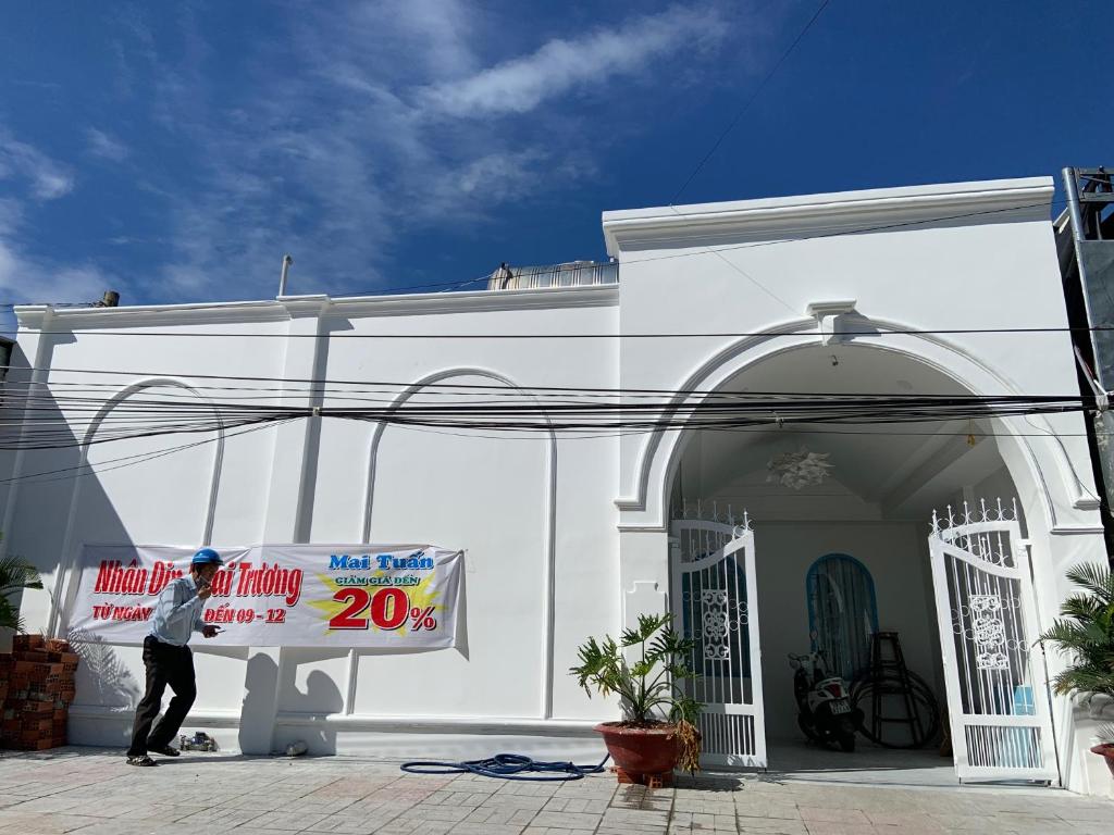 un hombre sosteniendo un cartel delante de un edificio blanco en Hotel MAI TUAN Nguyễn Văn Linh, en Phú Khương