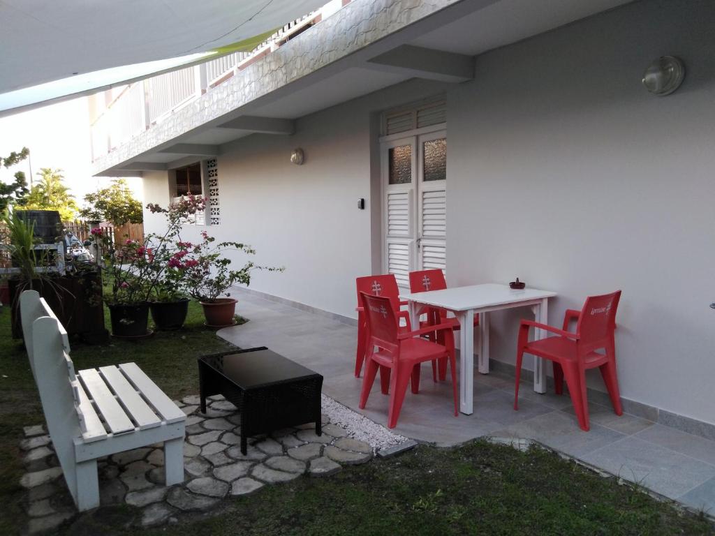 une terrasse avec des chaises rouges ainsi qu'une table et des chaises blanches. dans l'établissement F2 Rez de jardin CARBET, à Le Carbet