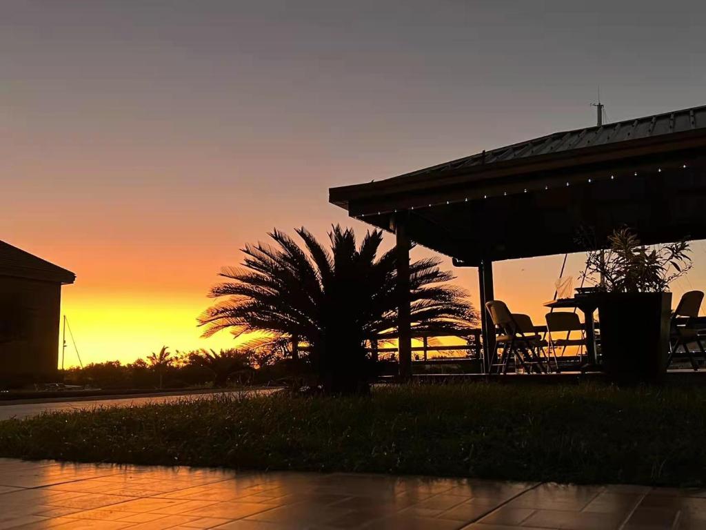 einen Sonnenuntergang hinter einem Pavillon mit Stühlen und einer Palme in der Unterkunft Gardenia Apartment-02 in Nadi