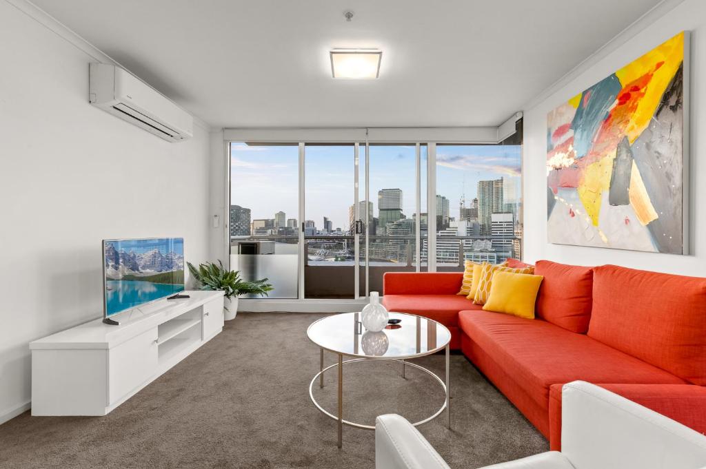 a living room with a red couch and a table at Exclusive Stays - Rivergarden in Melbourne