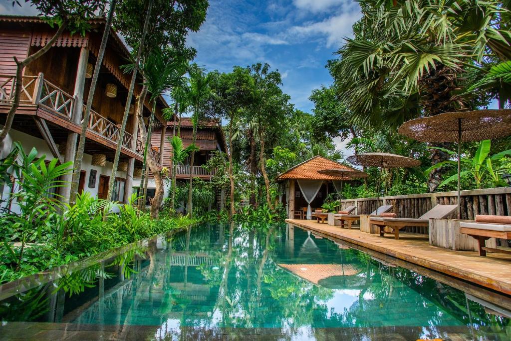 una piscina en un complejo con bancos y árboles en Isann Lodge, en Siem Reap