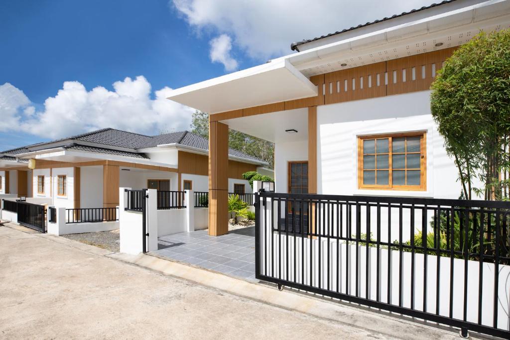 una casa con una valla negra delante de ella en Villa Sunrise Garden B190, en Ban Muang Mai