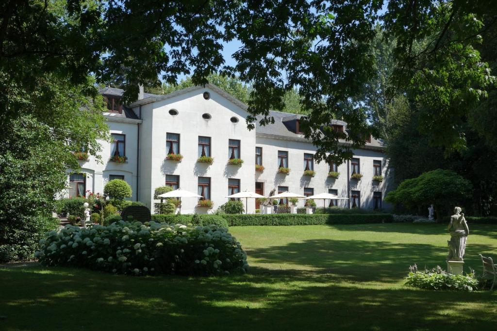 un gran edificio blanco con una estatua en el patio en Kasteel van Nieuwland, en Aarschot