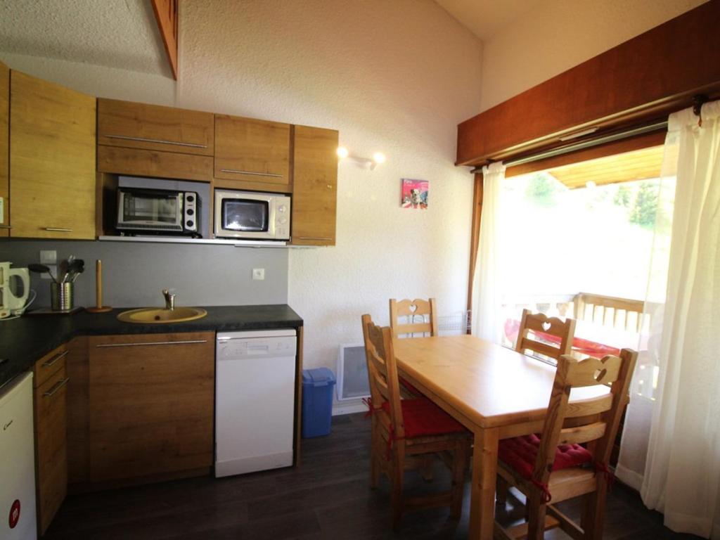 eine Küche mit einem Tisch und einer Mikrowelle sowie einem Tisch und Stühlen in der Unterkunft Appartement Auris, 1 pièce, 4 personnes - FR-1-297-298 in Auris