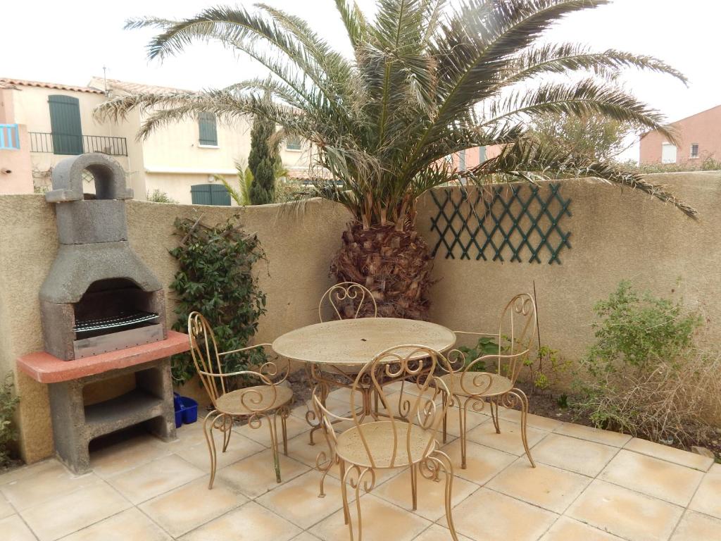 une terrasse avec une table, des chaises et une cuisinière dans l'établissement Villa à 50 m de la plage du Grazel pour 6 personnes, à Gruissan