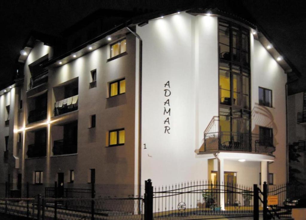 a building with a sign on the side of it at night at Adamar Jastrzębia Góra in Jastrzębia Góra