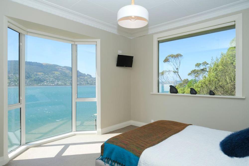 een slaapkamer met een groot raam met uitzicht op de oceaan bij Stairway to heaven in Dunedin