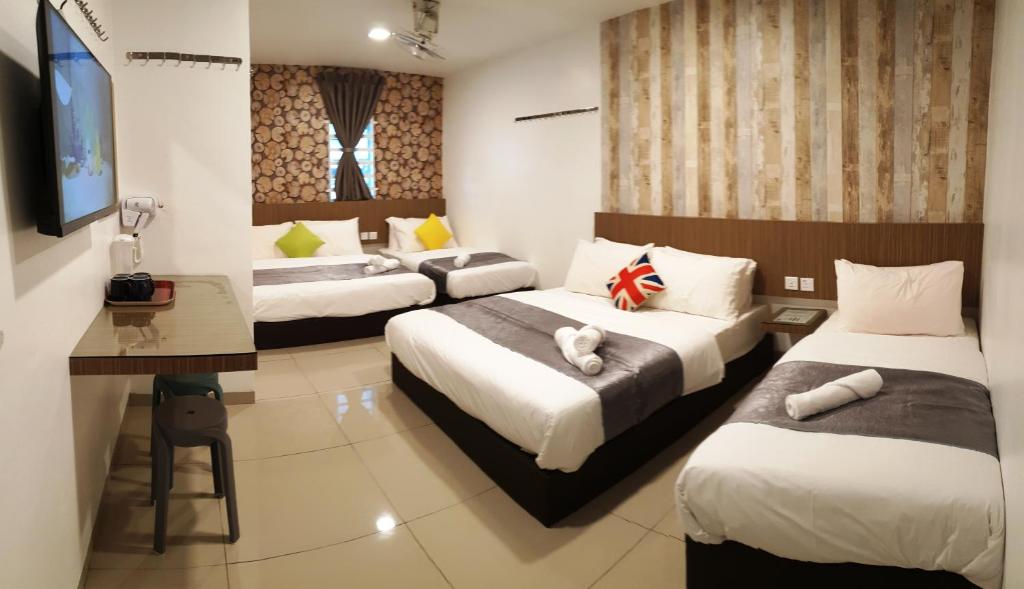 a hotel room with two beds and a desk at Garden 96 inn in Kuantan