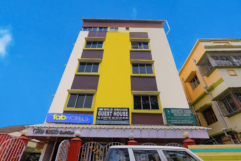 a tall yellow and white building with a sign on it at FabExpress Wild Orchid in Kolkata