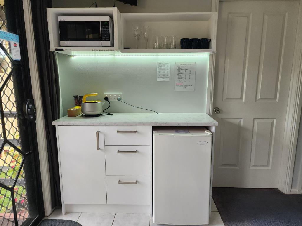 a white kitchen with a microwave and a refrigerator at Chateau Bass in Bass