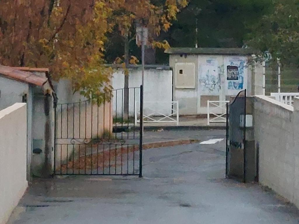 an open gate in a parking lot next to a building at La maison de Dannie in Gardanne