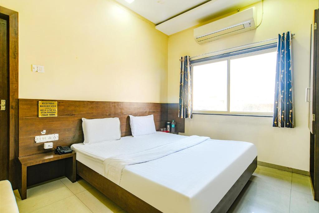 a bedroom with a large bed and a window at FabHotel Satyug Jaisinghpura in Ujjain