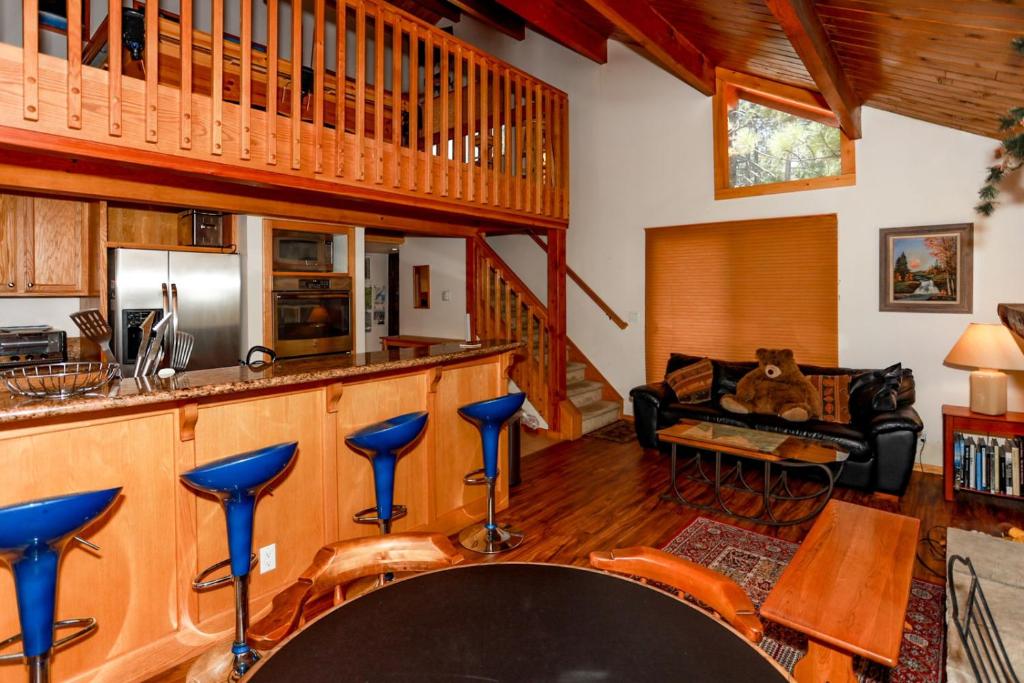 uma cozinha e sala de estar com um bar com bancos azuis em 1931 - Mountain Adventure home em Big Bear Lake