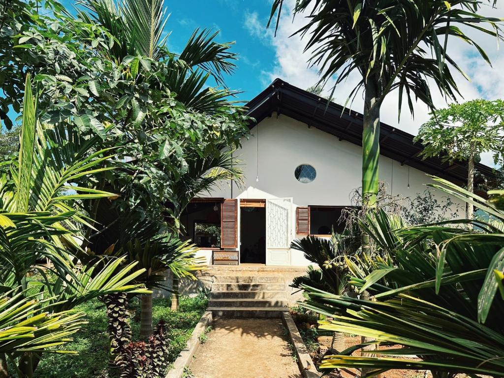 une maison blanche avec une porte au milieu des arbres dans l'établissement XOM Organic Farm Stay, à Pleiku