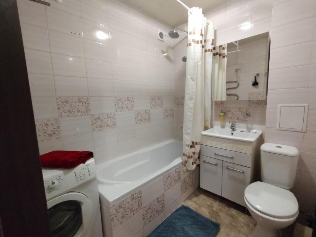 bagno con servizi igienici, lavandino e lavatrice di Очеровательная квартира в центре города a Obukhiv