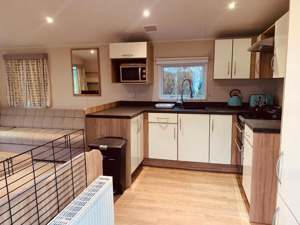 a small kitchen with white cabinets and a couch at 69 Newquay bay resort Pet friendly in Newquay