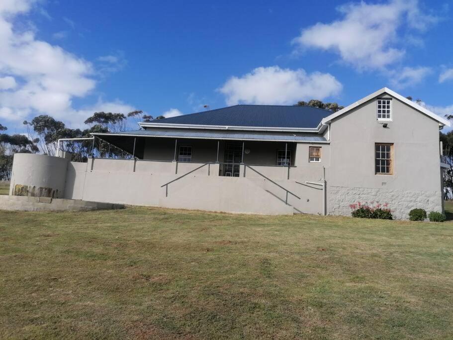 a white house with a fence and a yard at Bo-Plaas Farmhouse in Bredasdorp