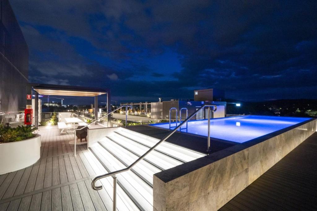 una piscina en la azotea de un edificio por la noche en Mulberry 2BR-2BA Rooftop Pool, BBQ, WiFi & Netflix - Central Location en Canberra