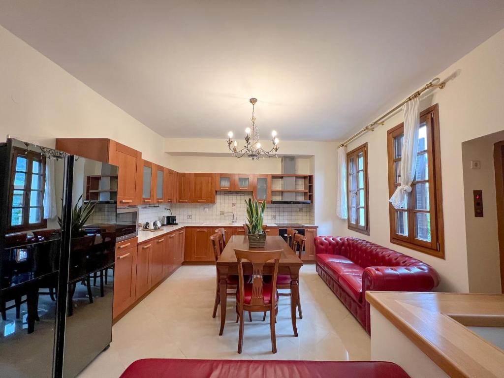 kuchnia i salon ze stołem i czerwoną kanapą w obiekcie Villa Voulgari w mieście Janina