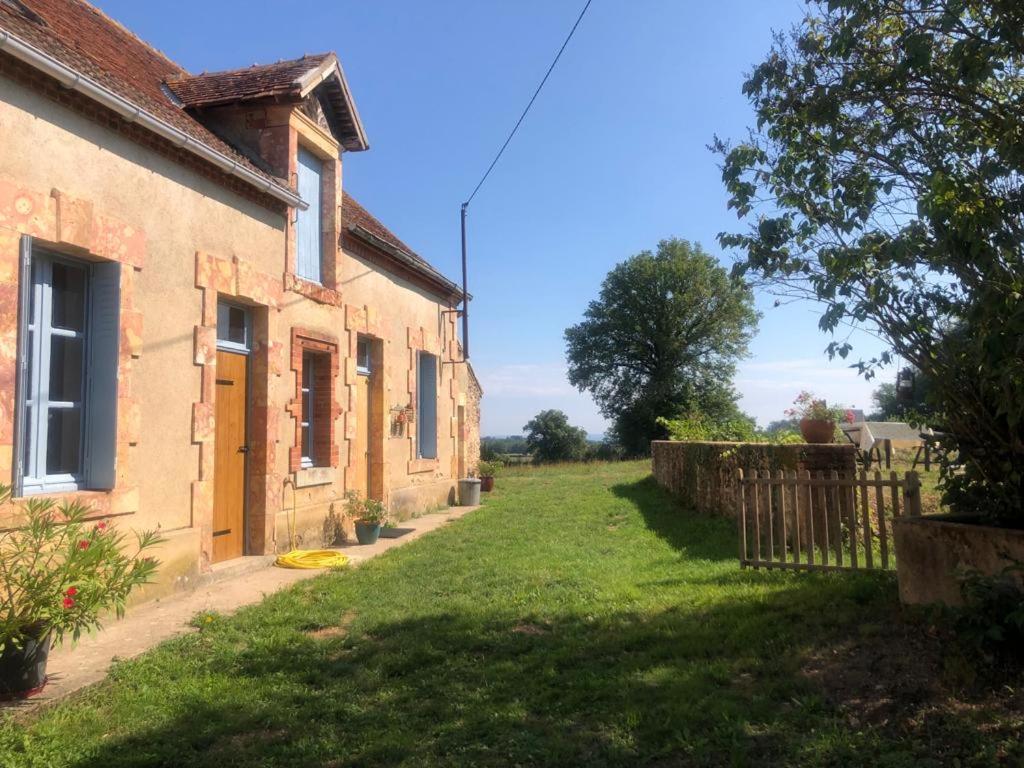 ein Haus mit einem Rasenplatz neben einem Gebäude in der Unterkunft Le Tarde - Crécerelle in Saint-Désiré