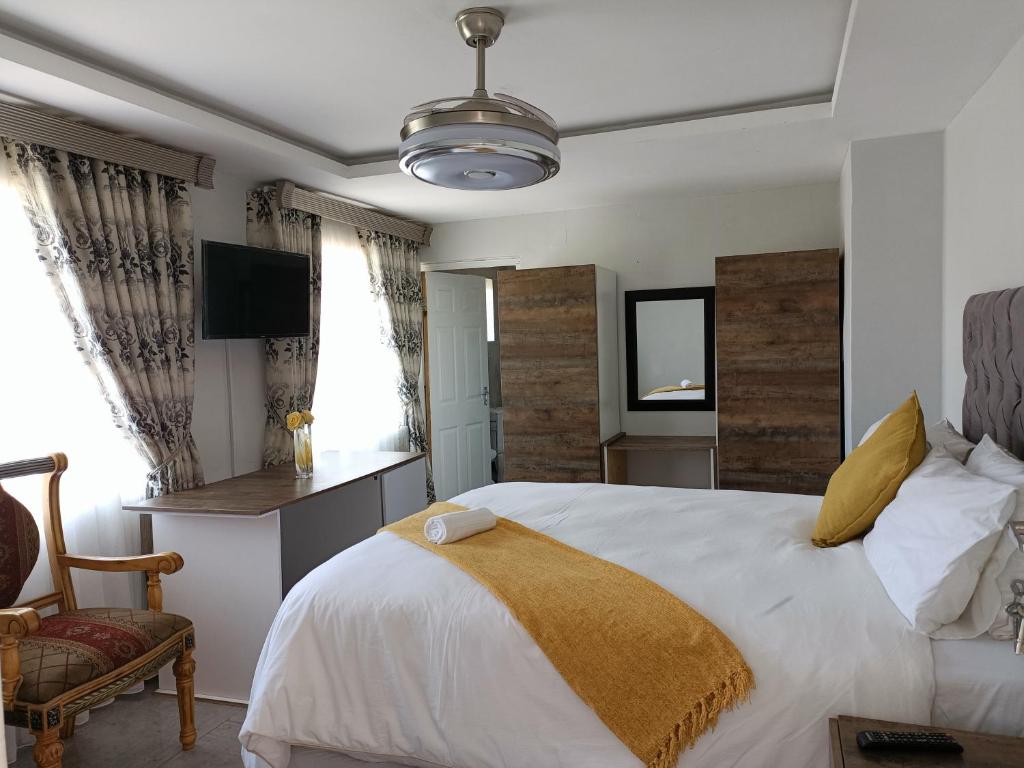 a bedroom with a large white bed and a chair at EYEZULU Guesthouse in Pinetown