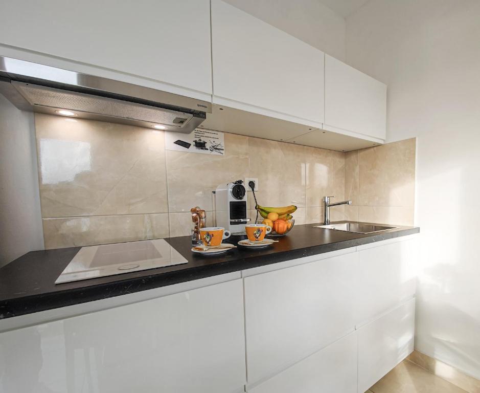 una cocina con armarios blancos y fregadero en Apartments - Villa Sabrina, en Brela