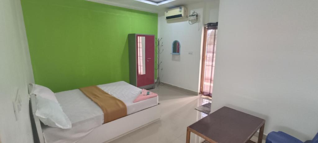 Cette chambre comprend un lit et un mur vert. dans l'établissement Hotel Greenvalley Residency, à Punalūr