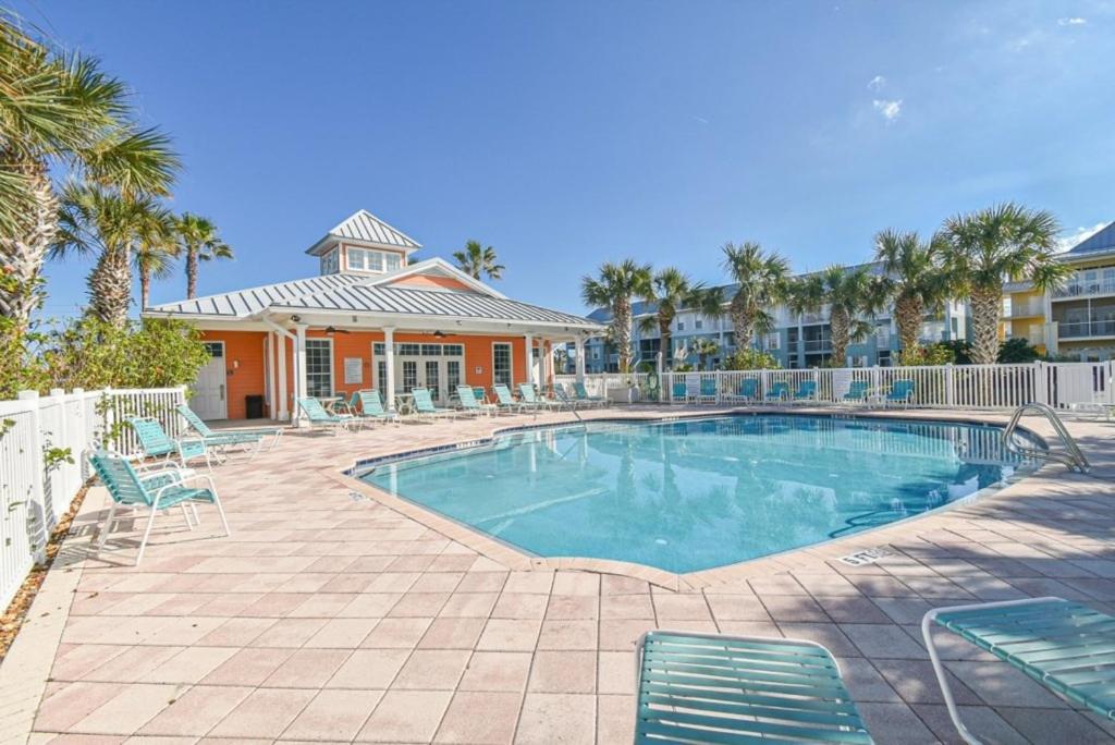 a swimming pool with chairs and a house at Seaside At Anastasia 202 Condo in Saint Augustine