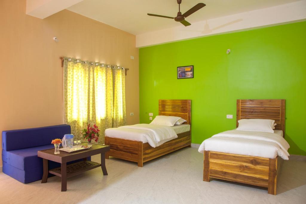 a green bedroom with two beds and a blue couch at Rains Inn Eco Hotel in Diphu