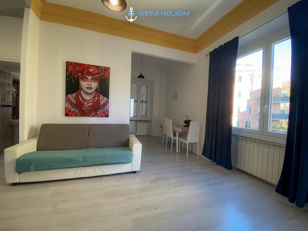 een woonkamer met een bank en een schilderij aan de muur bij Casa Vacanze Al Curvone in Lido di Ostia