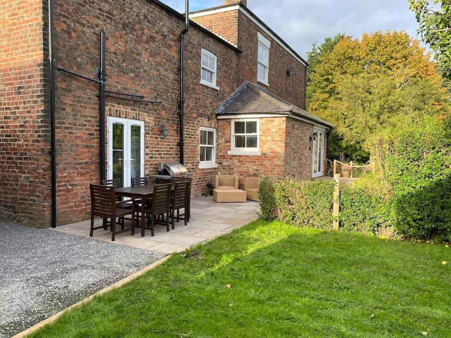 a patio with a table and chairs in front of a brick building at The Annex: 2 bedroom cottage, countryside, peaceful getaway with garden in Easingwold