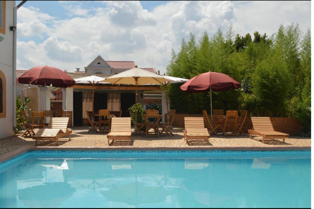 a swimming pool with chairs and umbrellas and tables at Iarimbato Hotel in Antananarivo