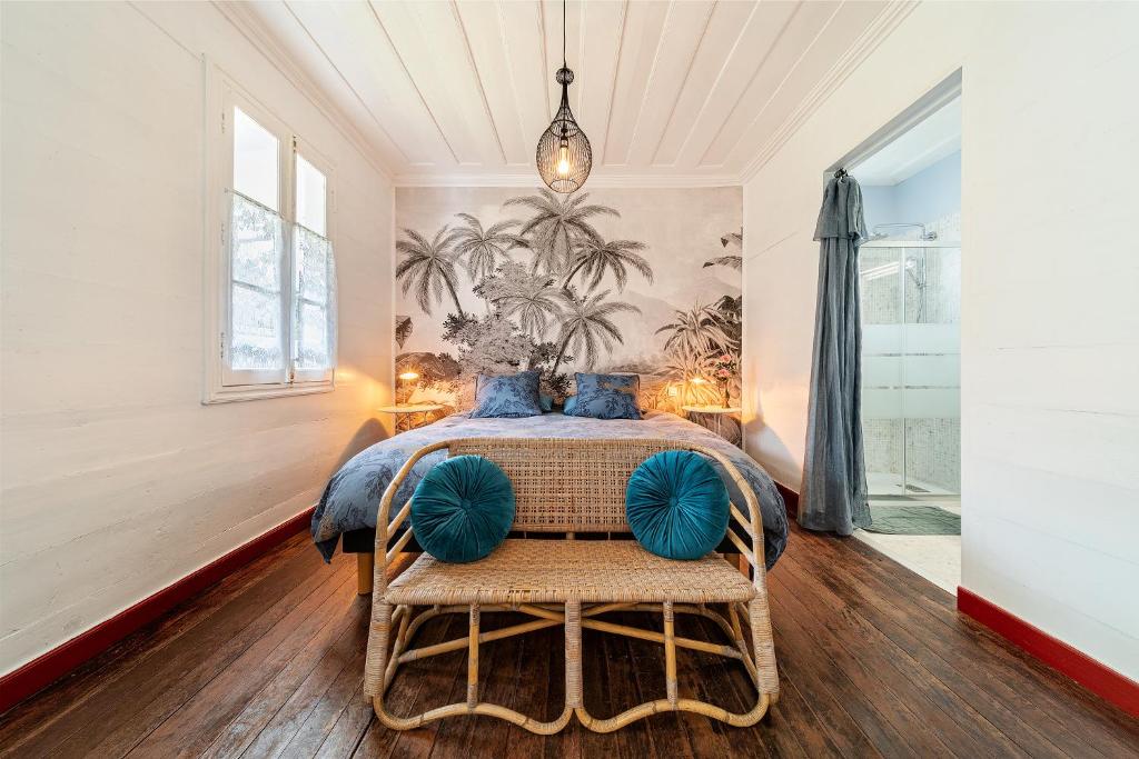 a bedroom with a bed with blue pillows at La Villa Blanche, Hell-Bourg in Salazie