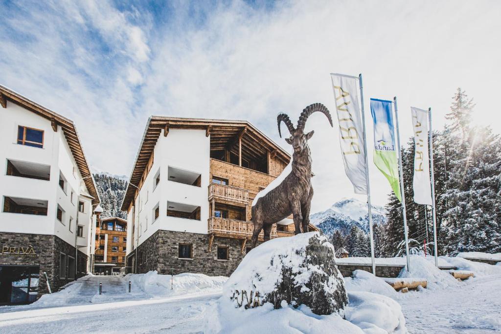 a statue of a goat in the snow in front of a building at PRIVÀ Alpine Lodge in Lenzerheide