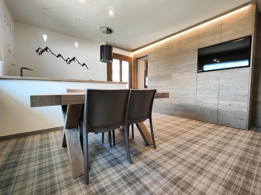 a dining room with a table and chairs and a tv at Hostdomus - Helsinki Suite in Sestriere