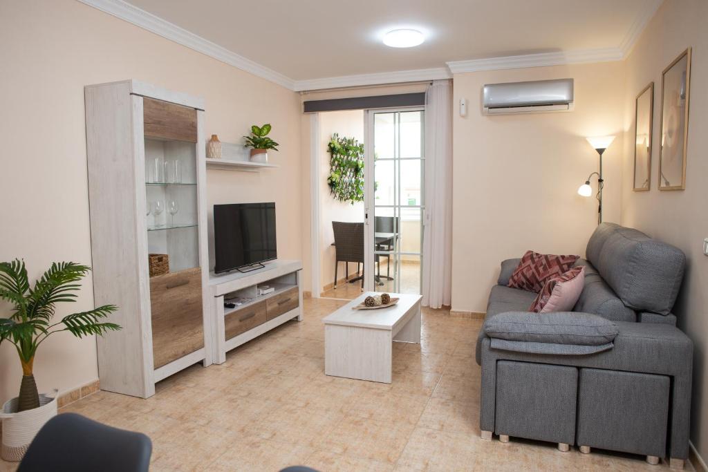 ein Wohnzimmer mit einem Sofa und einem TV in der Unterkunft Apto ISA: amplio y acogedor apto de 75m con terraza, aire acondicionado y parking gratuito in Los Abrigos