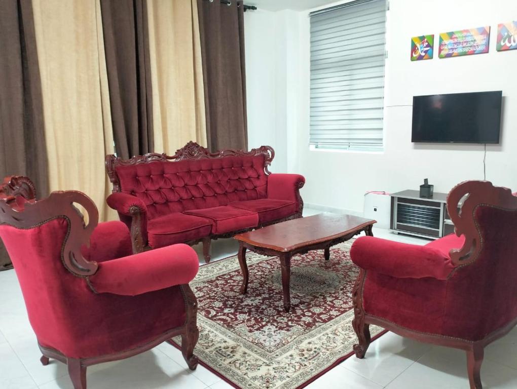 a living room with a red couch and two chairs at Mahzan Homestay in Jitra