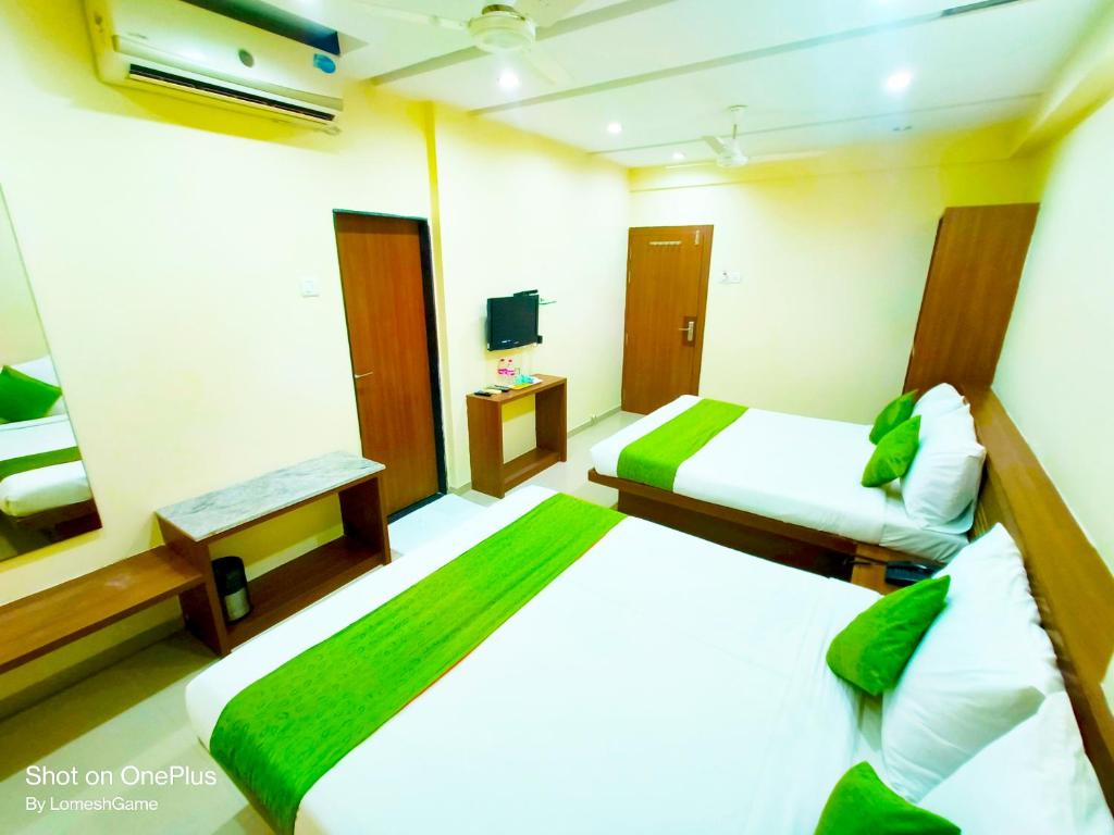 a hotel room with two beds and a television at SAI SRUSHTI by NEEM SQUARE in Shirdi