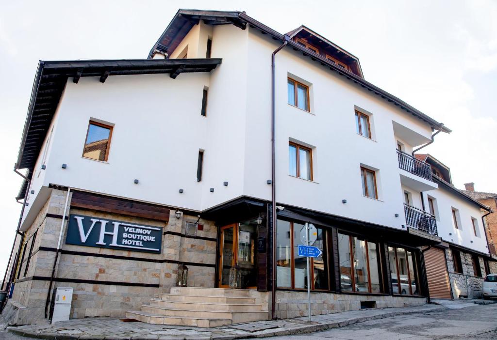 a white building with a sign in front of it at Velinov Boutique Hotel in Bansko