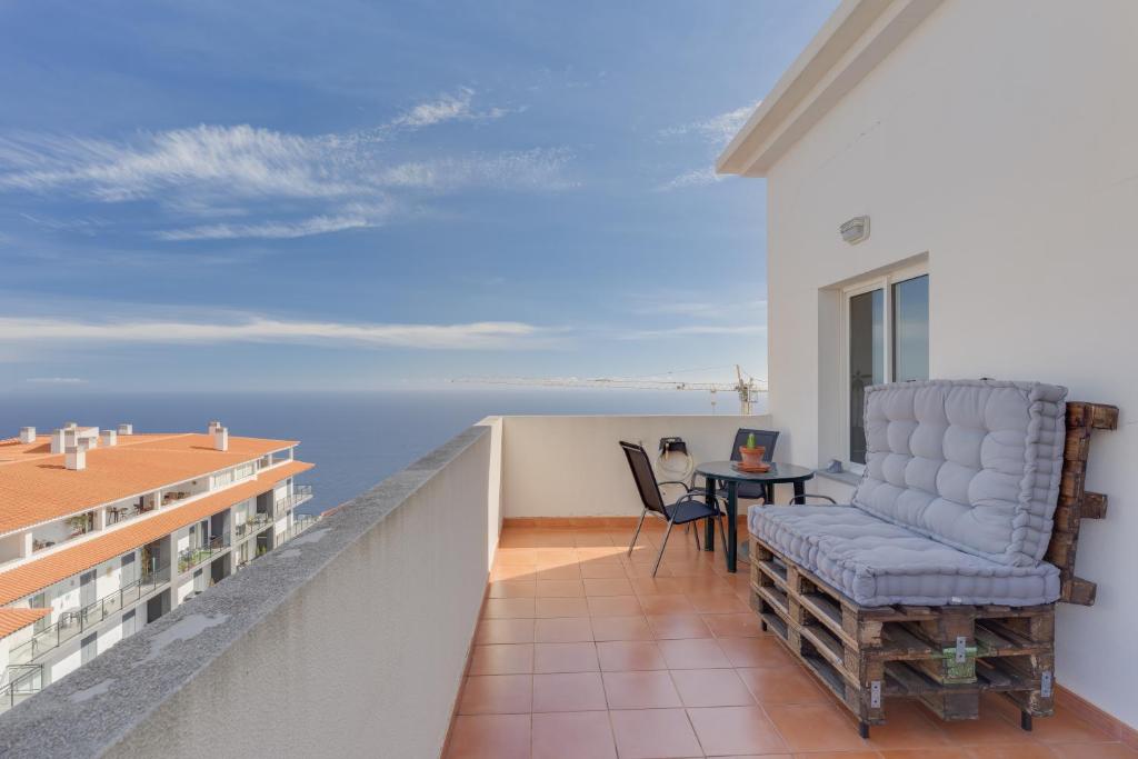 a balcony with a chair and a table at Alta do Garajau I in Caniço