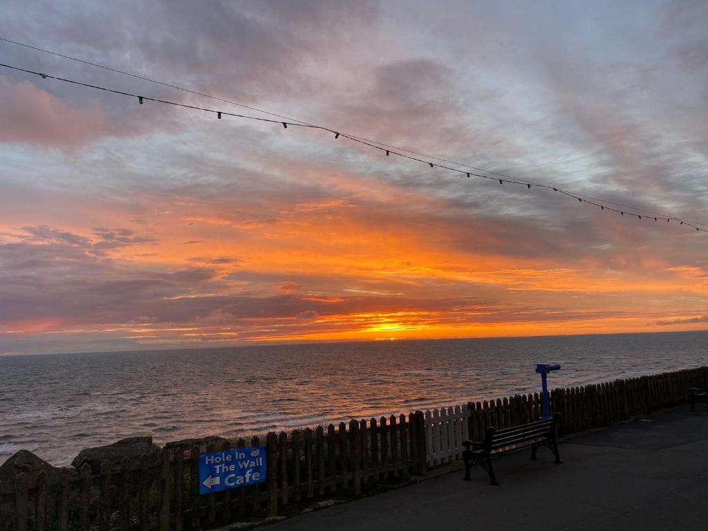 a bench in front of the ocean at sunset at Kings Court Hotel in Blackpool