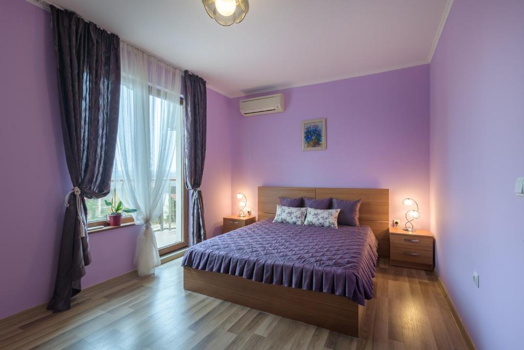 a purple bedroom with a bed and a window at Infinity View Shkorpilovci in Shkorpilovtsi