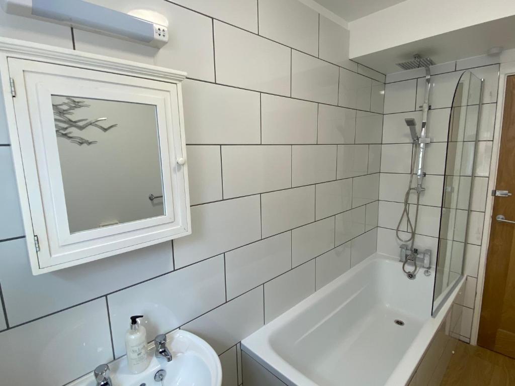 een witte badkamer met een wastafel en een bad bij The North Bay Hideaway, Scarborough in Scarborough