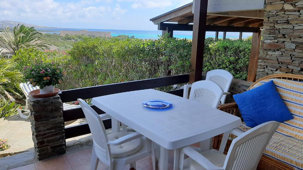 une table blanche et des chaises sur un balcon avec l'océan dans l'établissement La Finestra su Stintino 2, à Stintino