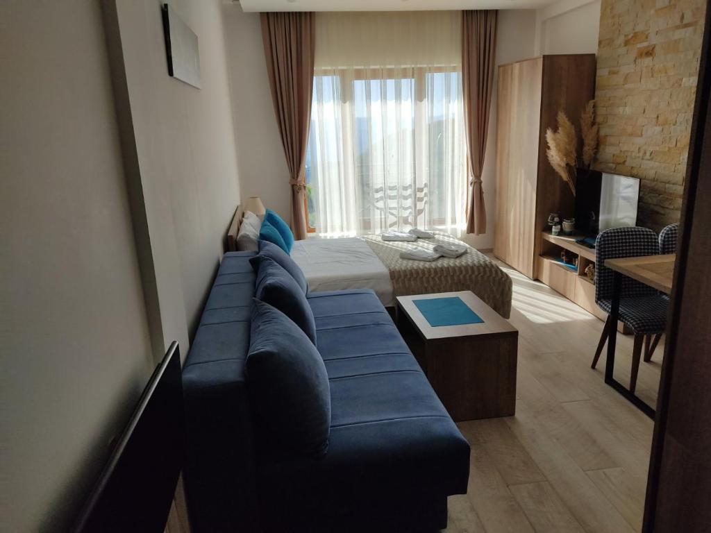 Una sala de estar con un sofá azul y una cama. en Apartman Adelfes P16, Milmari Resort, en Kopaonik
